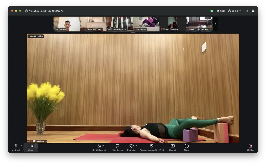 Học viên nằm thư giãn với gạch tập yoga hỗ trợ dưới lưng trong buổi tập online